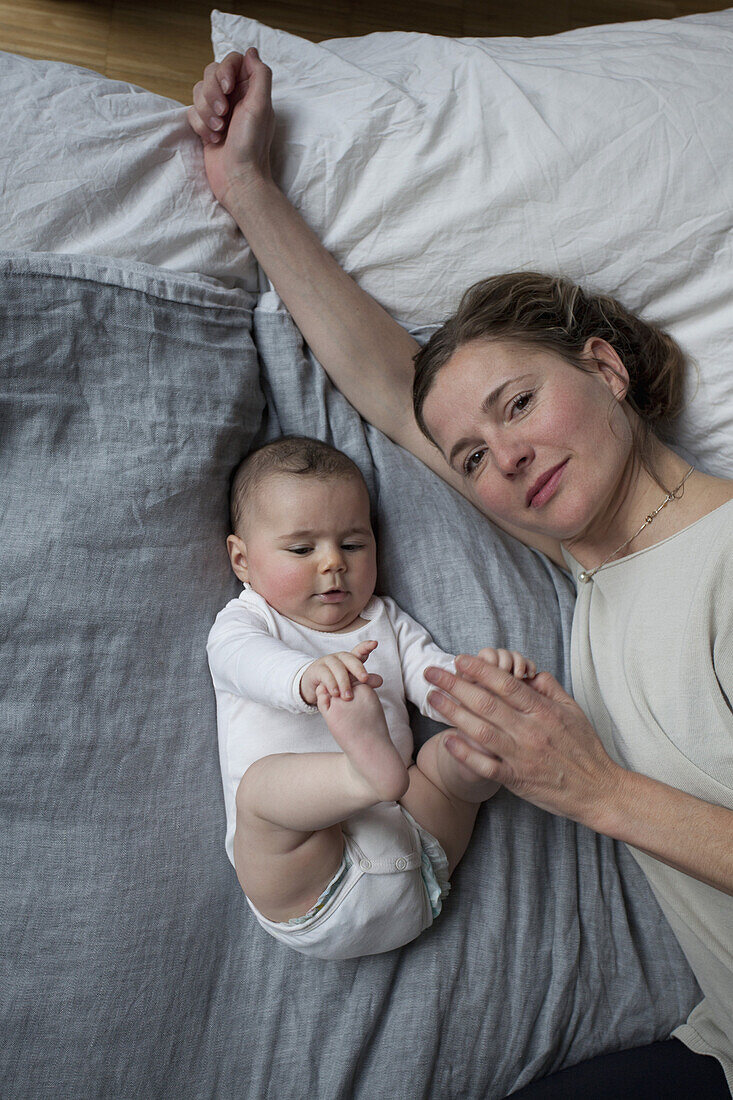 High angle portrait of mother with baby girl lying on mattress
