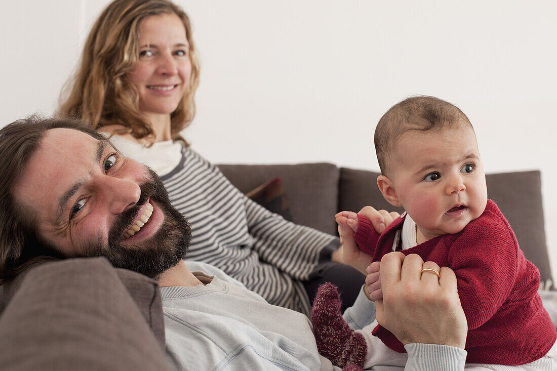 Portrait of happy parents with baby girl on sofa