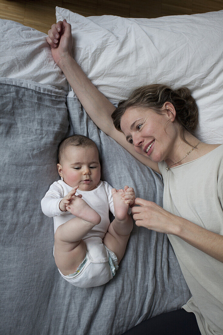 Directly above shot of smiling mother looking at baby girl at home