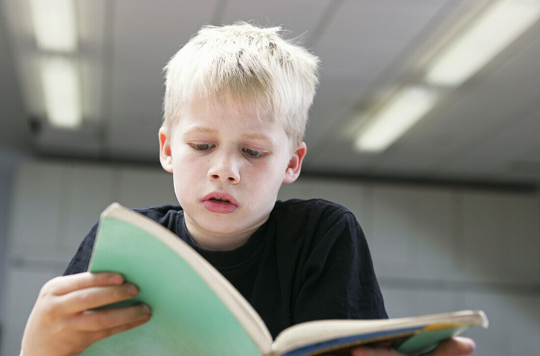 Front view of a small boy attentively reading a book