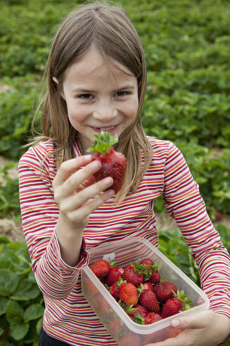 Portrait of girl holding strawberry box, smiling