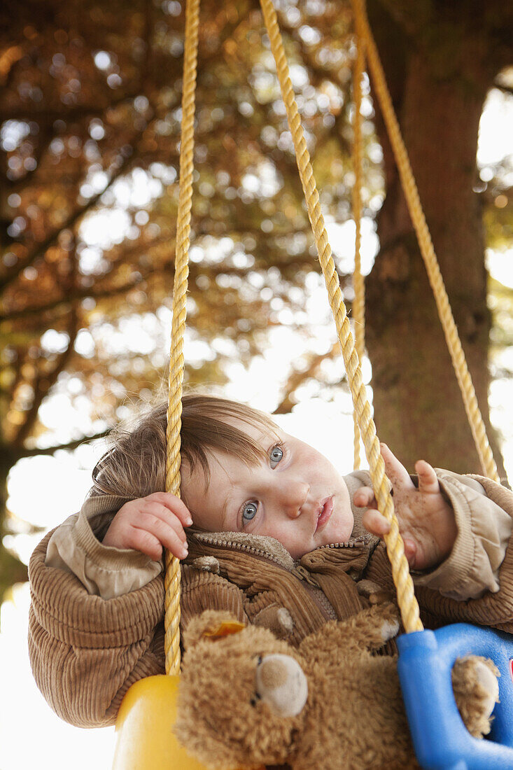 Baby girl sitting on swing, looking away
