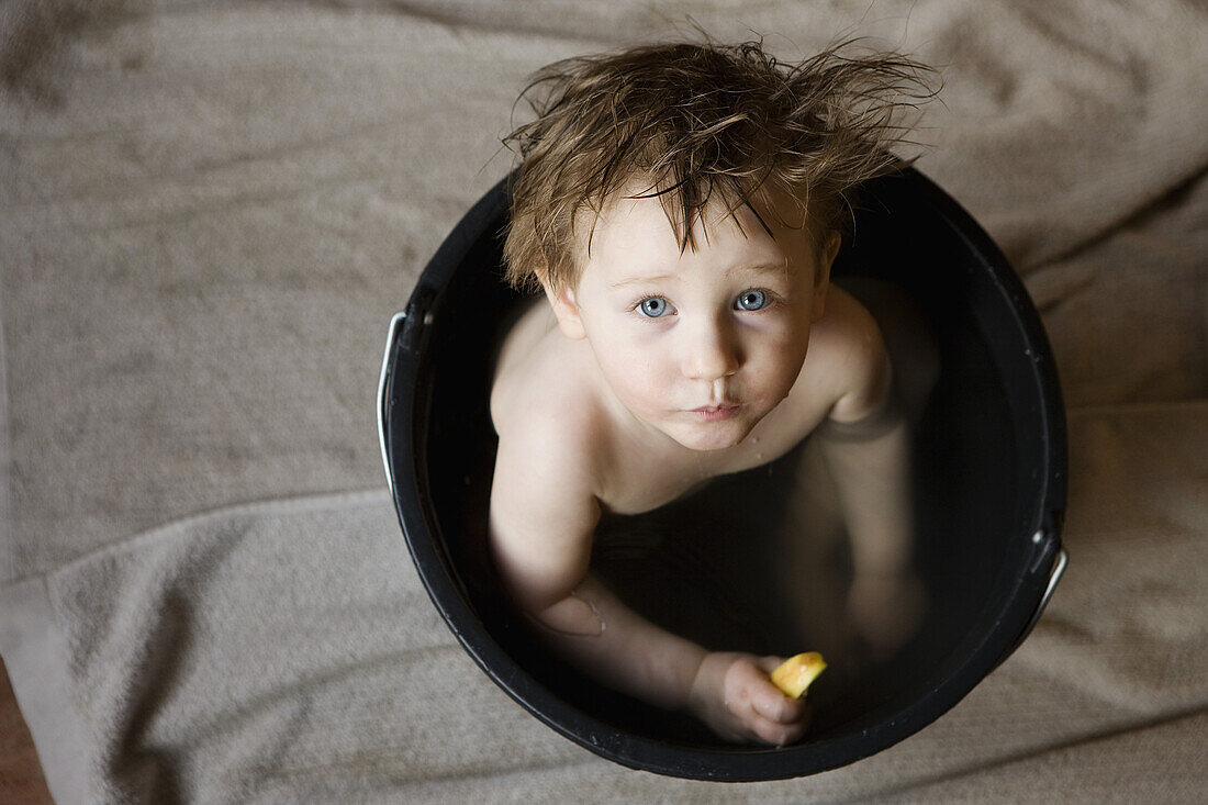 Baby girl taking bath in bucket, portrait
