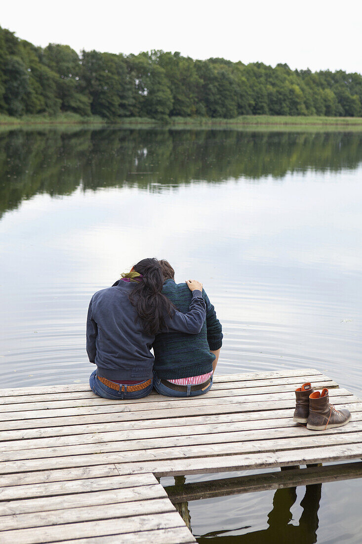 Young couple sitting on pier, rear view