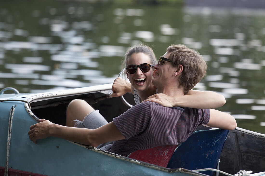 Young couple riding paddle boat, laughing
