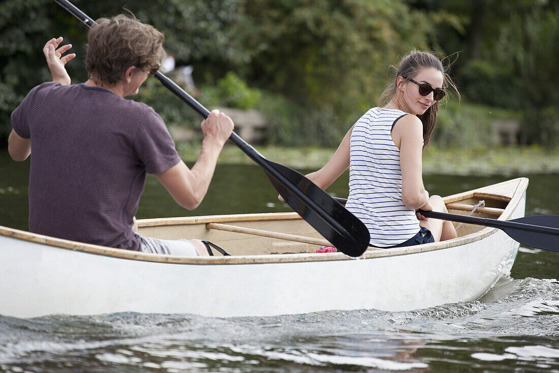 Young couple rowing canoe on lake