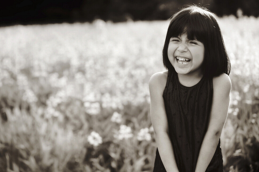A young girl in a field laughing in the sunlight