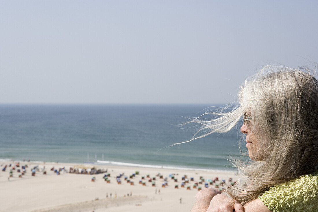A mature adult woman looking out over a beach