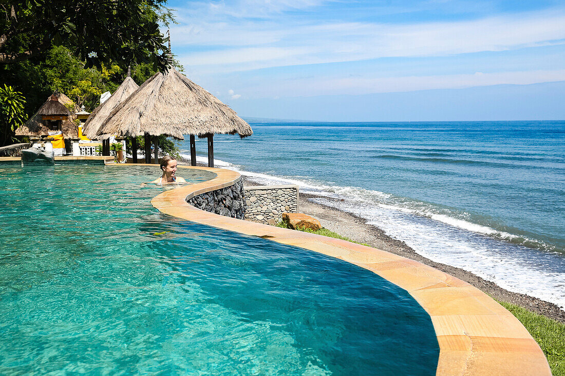 Frau in einem Überlaufpool mit Blick auf Indischen Ozean, Hotelanlage Wawa-Wewe II, Amed, Bali, Indonesien
