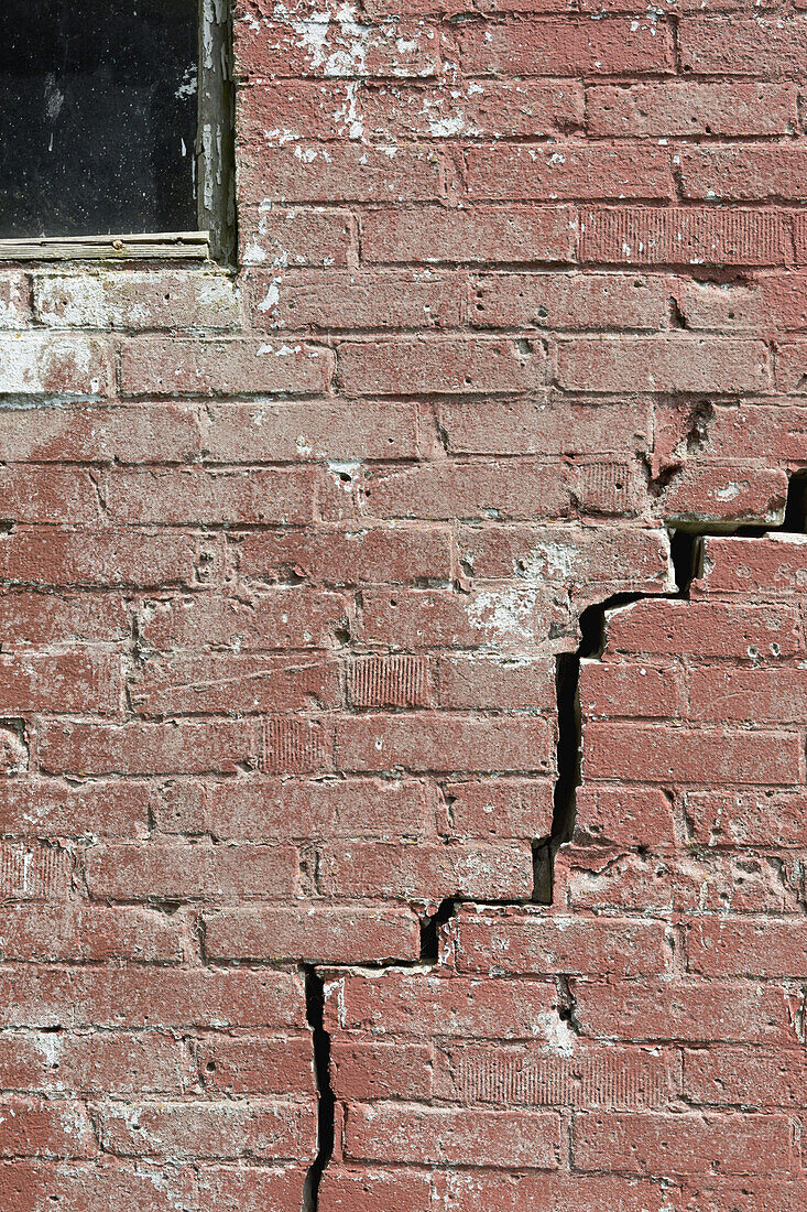 Close-up of a crack running through a red brick wall