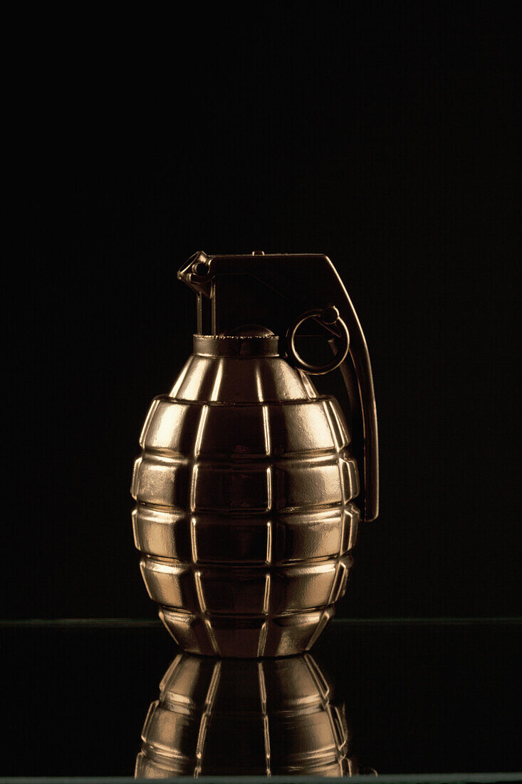 A grenade on a shiny surface, black background