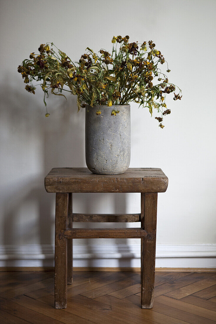 A stone vase full of dead flowers