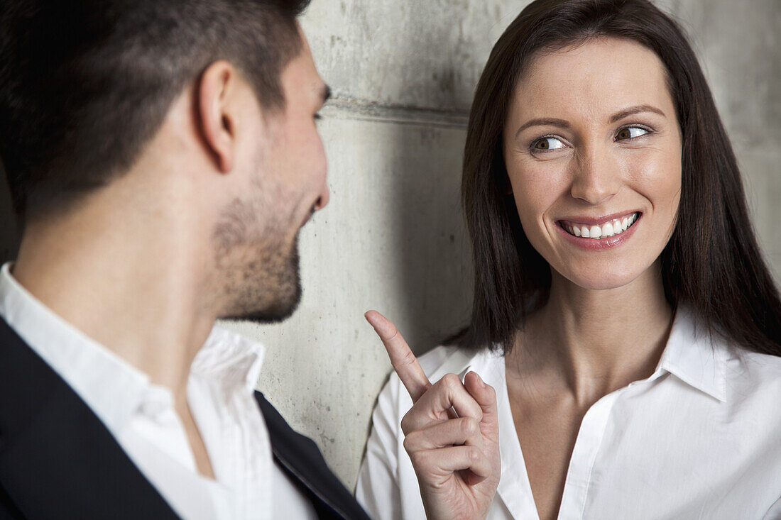 Eine lächelnde Geschäftsfrau schimpft mit einem Geschäftsmann