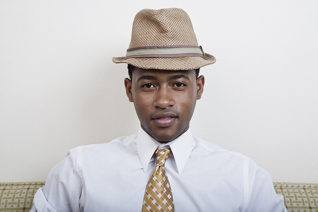 A young black man wearing a hat and tie