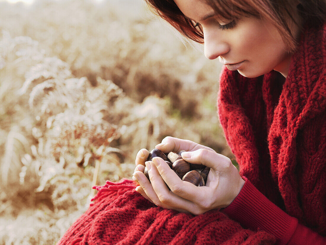 A woman considering a handful of chestnuts she's holding