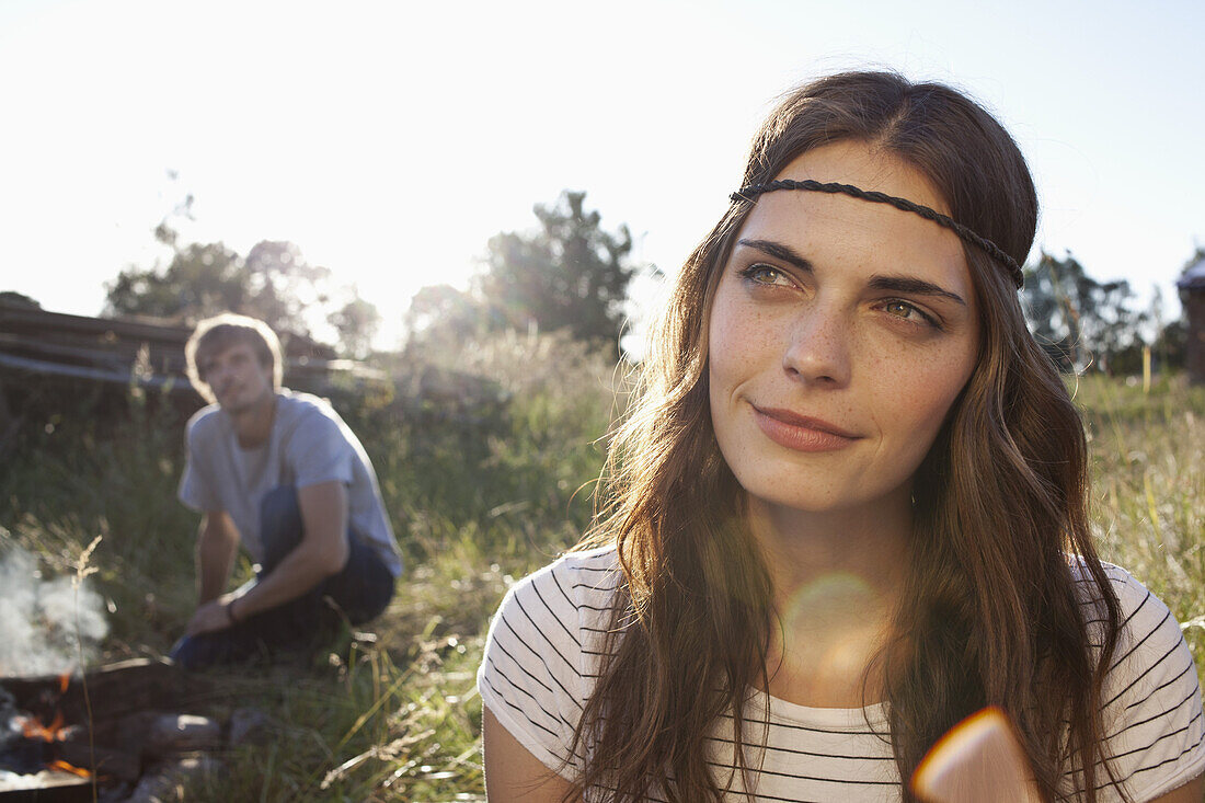Profile of Long haired girl in field, and guy in the background looking at her
