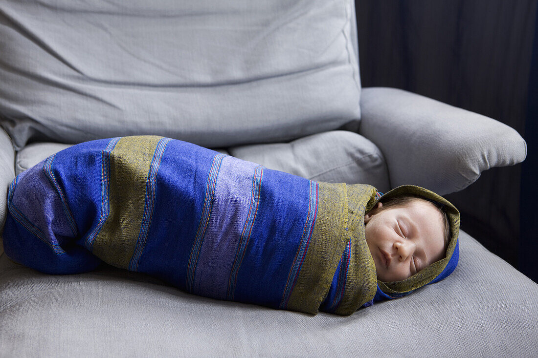 A newborn baby swaddled in a striped blanket