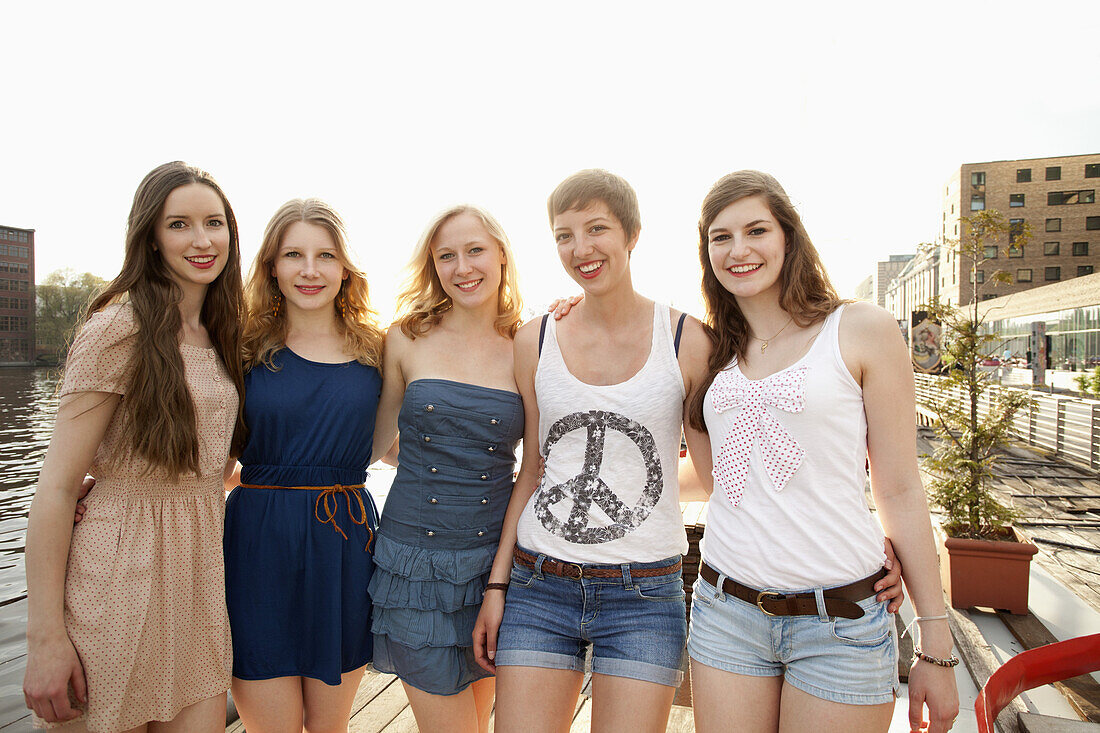 Five cheerful young female friends standing a row, Spree River, Berlin, Germany
