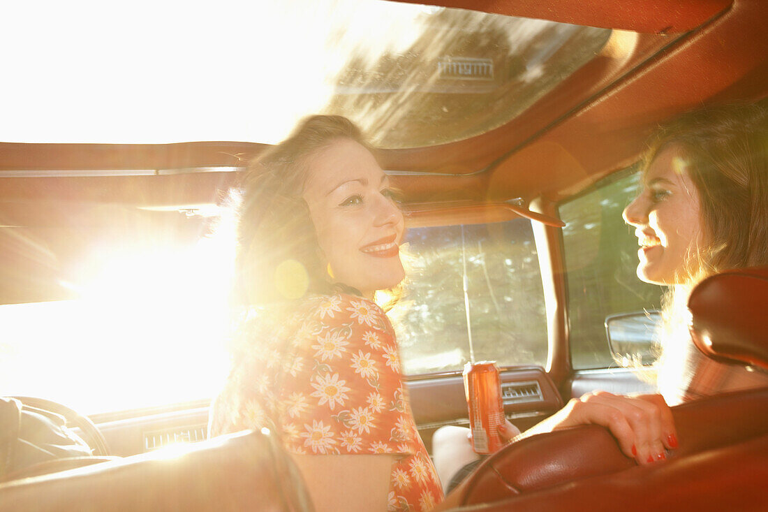 Two rockabilly women having fun in the front seat of a vintage car