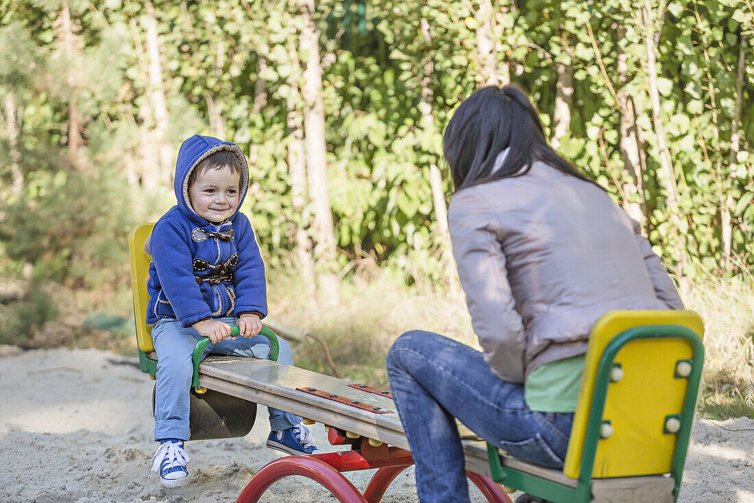 A young mother and her young son on a seesaw at a playground