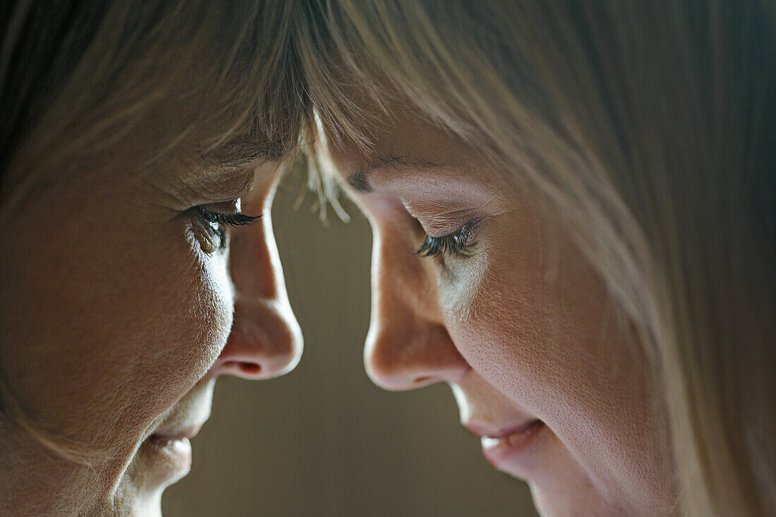 An adult woman touching foreheads with her mother, close-up