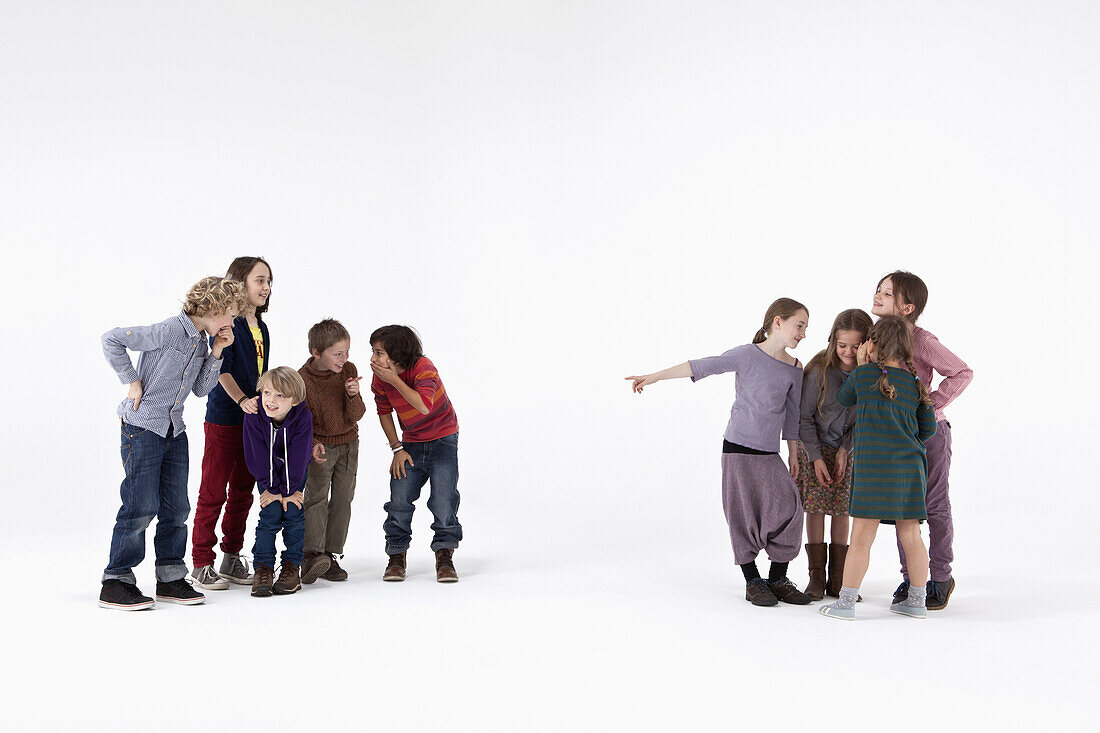 A group of boys laughing while a group of girls gossips about them