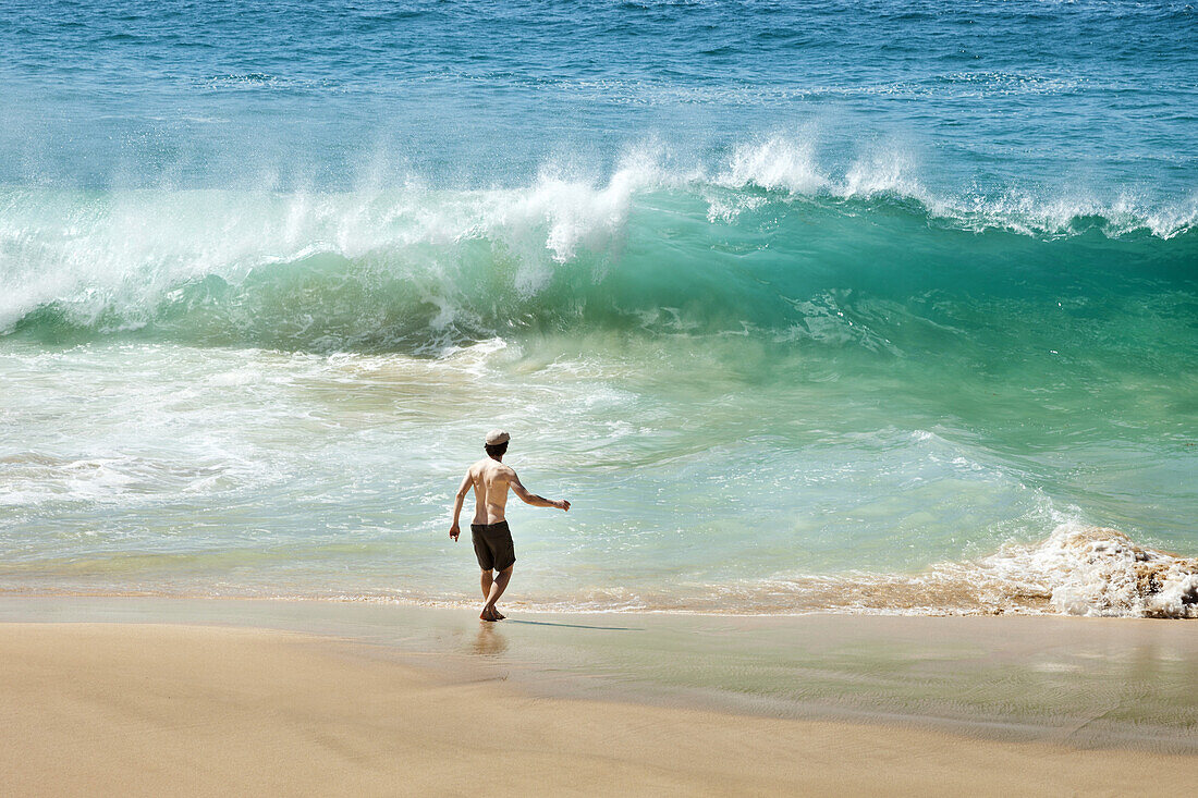 Man facing wave on beach in La Graciosa, Canary Islands, Spain