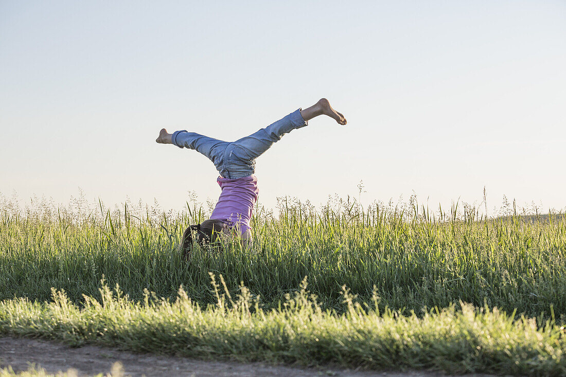 A young girl doing a handstand with her legs apart in a split