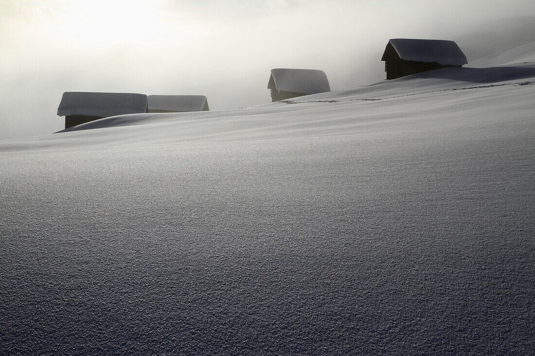 Four log cabins on smooth snowy landscape