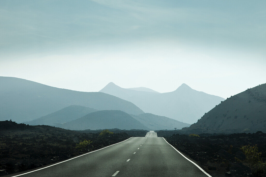 Empty road leading towards mountains in Lanzarote, Canary Islands, Spain