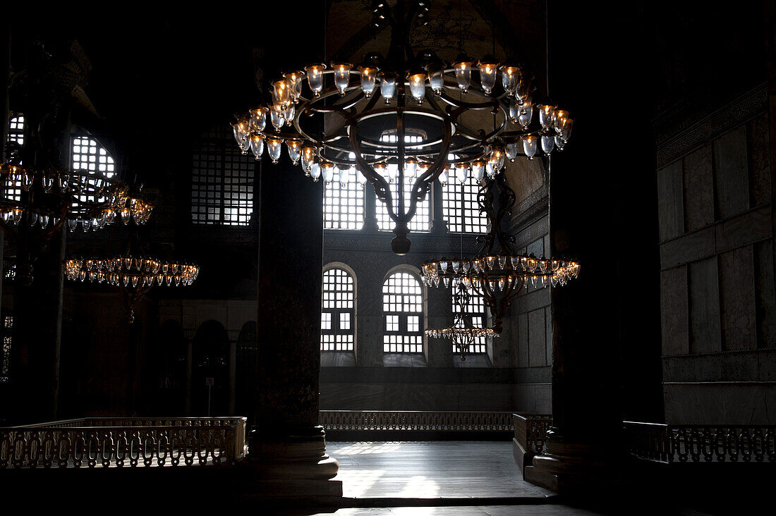 Chandeliers hanging in a shadowed interior of the Blue Mosque, Istanbul, Turkey
