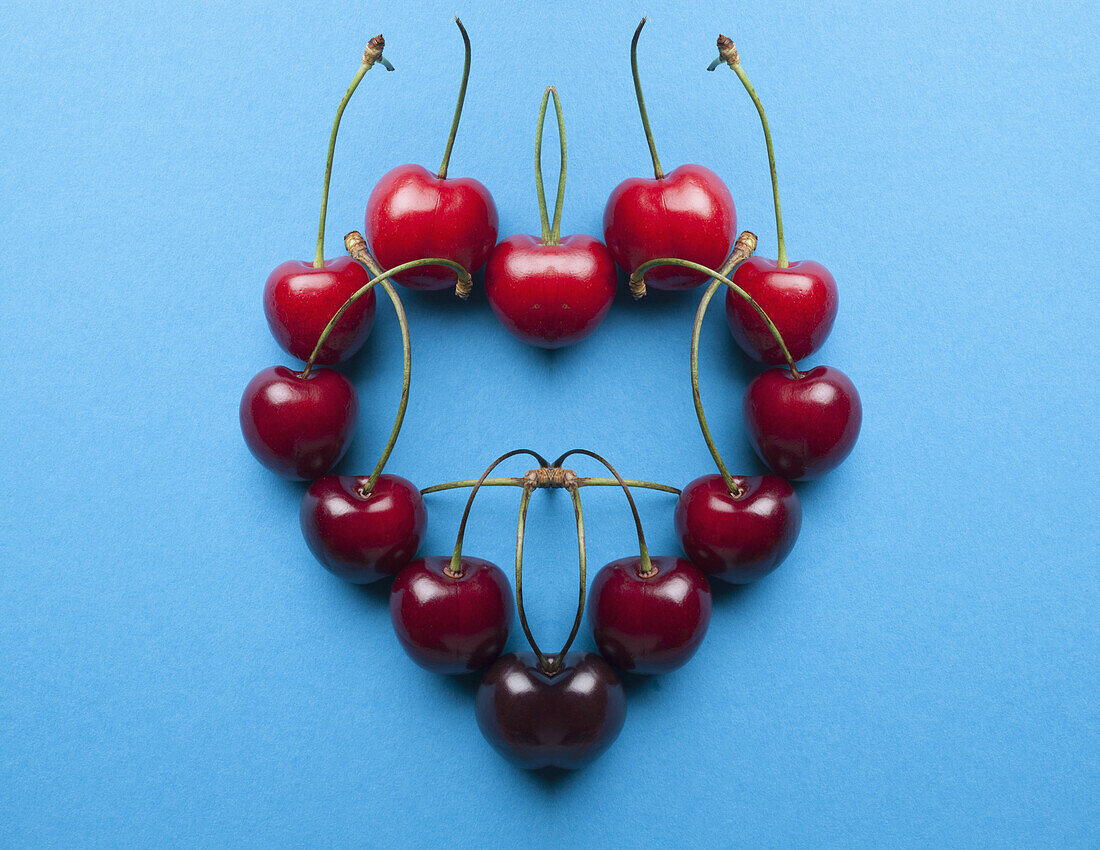 A digital composite of mirrored images of an arrangement of cherries in a heart shape