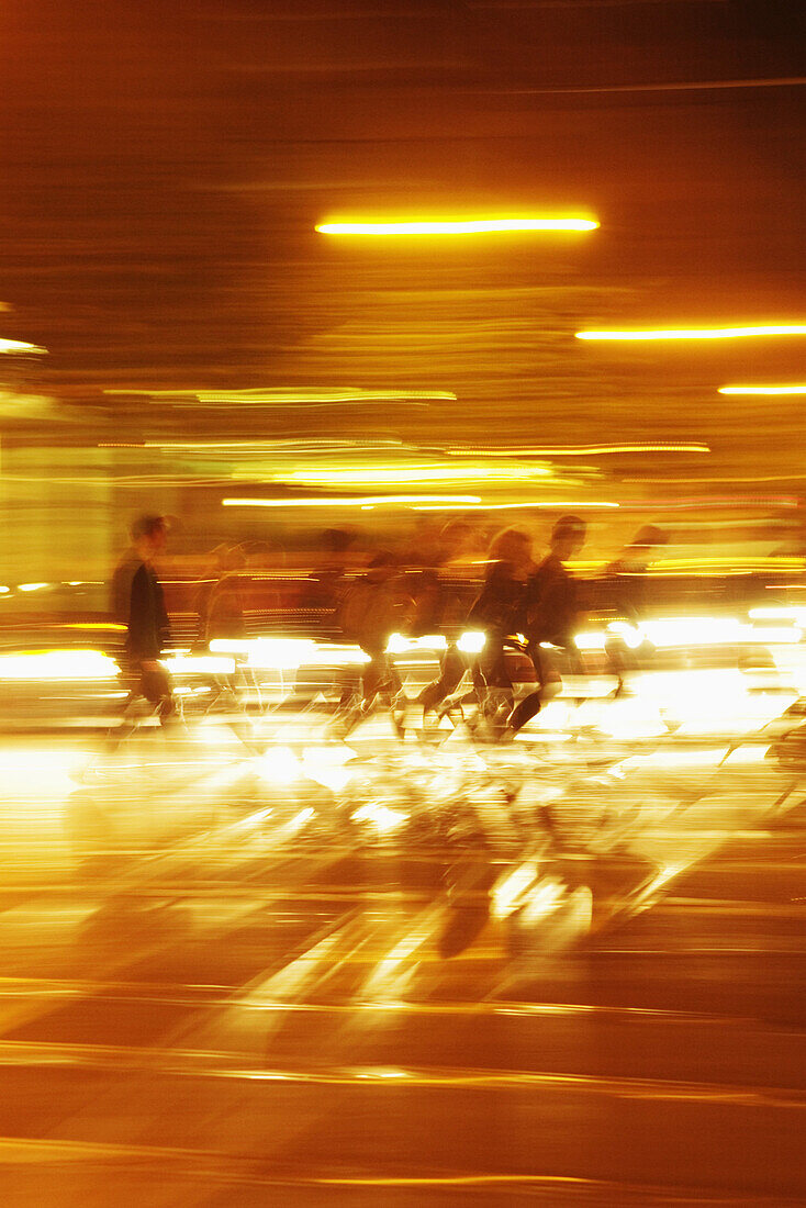 Blurred motion of people walking in illuminated tunnel