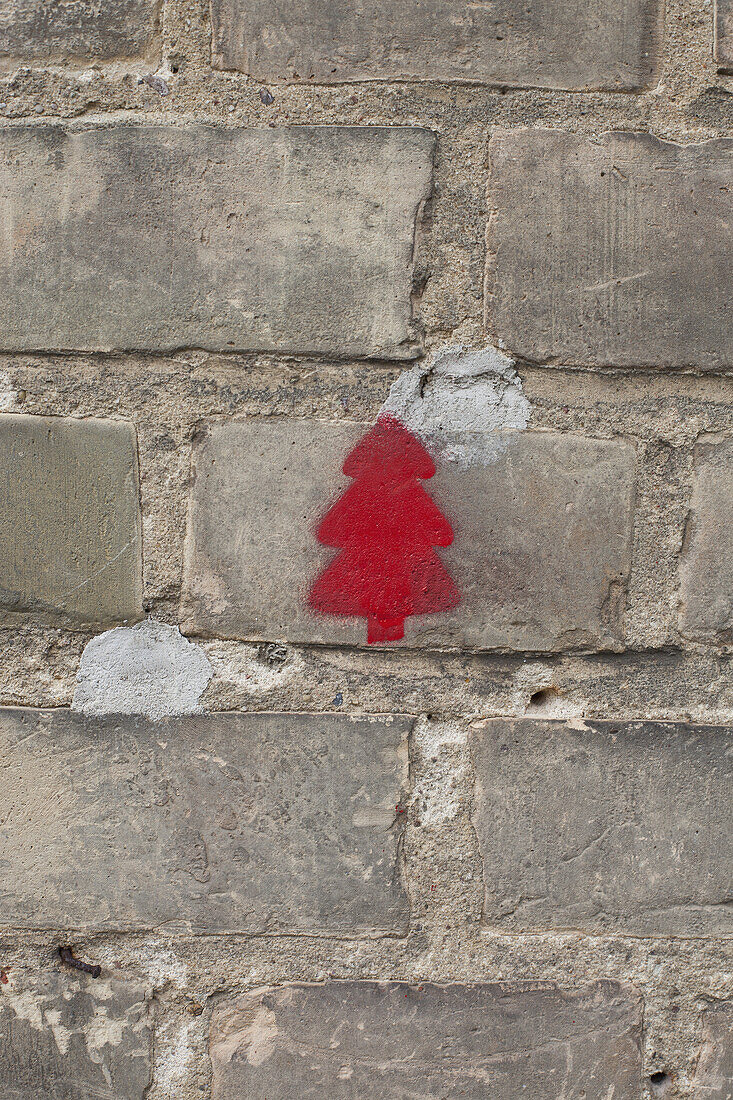 A red Christmas tree stenciled on a brick wall
