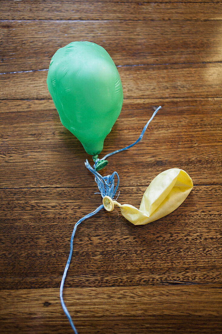 Two deflated balloons on a wooden table