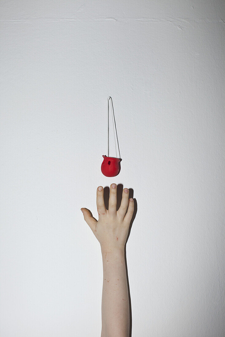 A hand reaching up a wall for a clown's nose