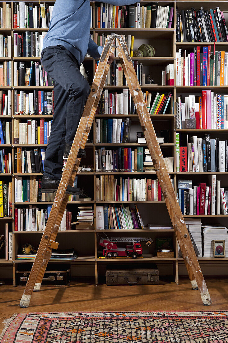 A man climbing up a ladder in a home library