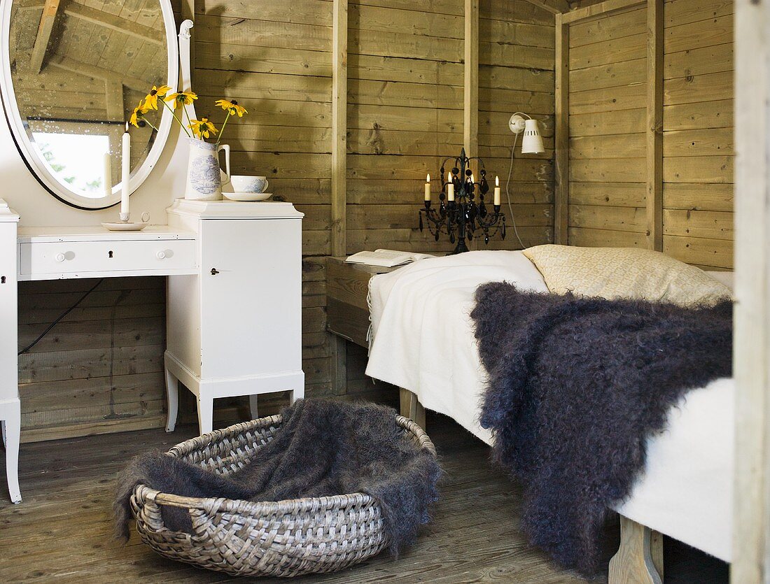 A rustic room with wooden walls - a fur on a bed and a white make-up table