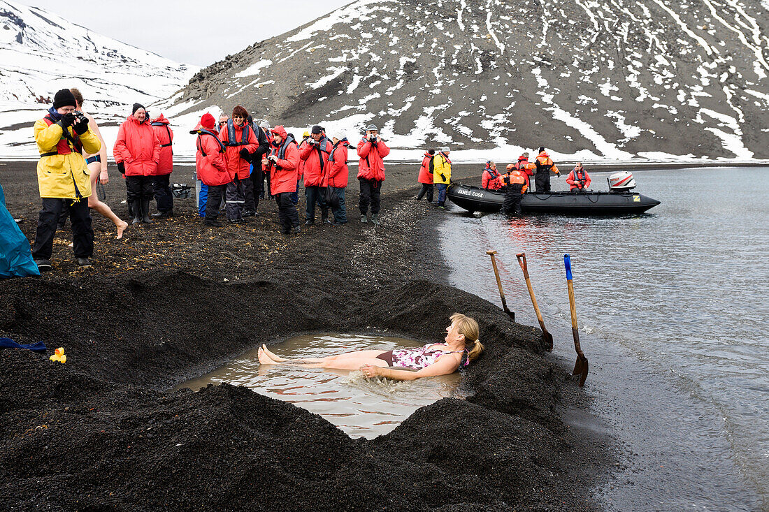 Tourists bathing in the hot springs of the crater lake of Deception Island, South Shetland Islands, Antarctica