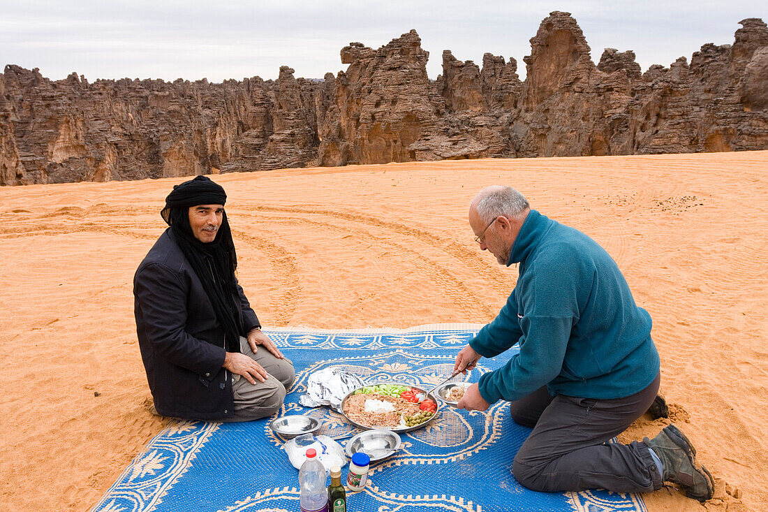 Tuareg und Tourist essen in traditioneller Weise, Tassili Maridet, Libyen, Afrika