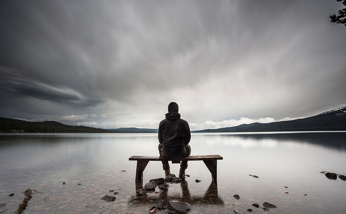 Person on a bench at the edge of a lake, Douglas County, Oregon, USA