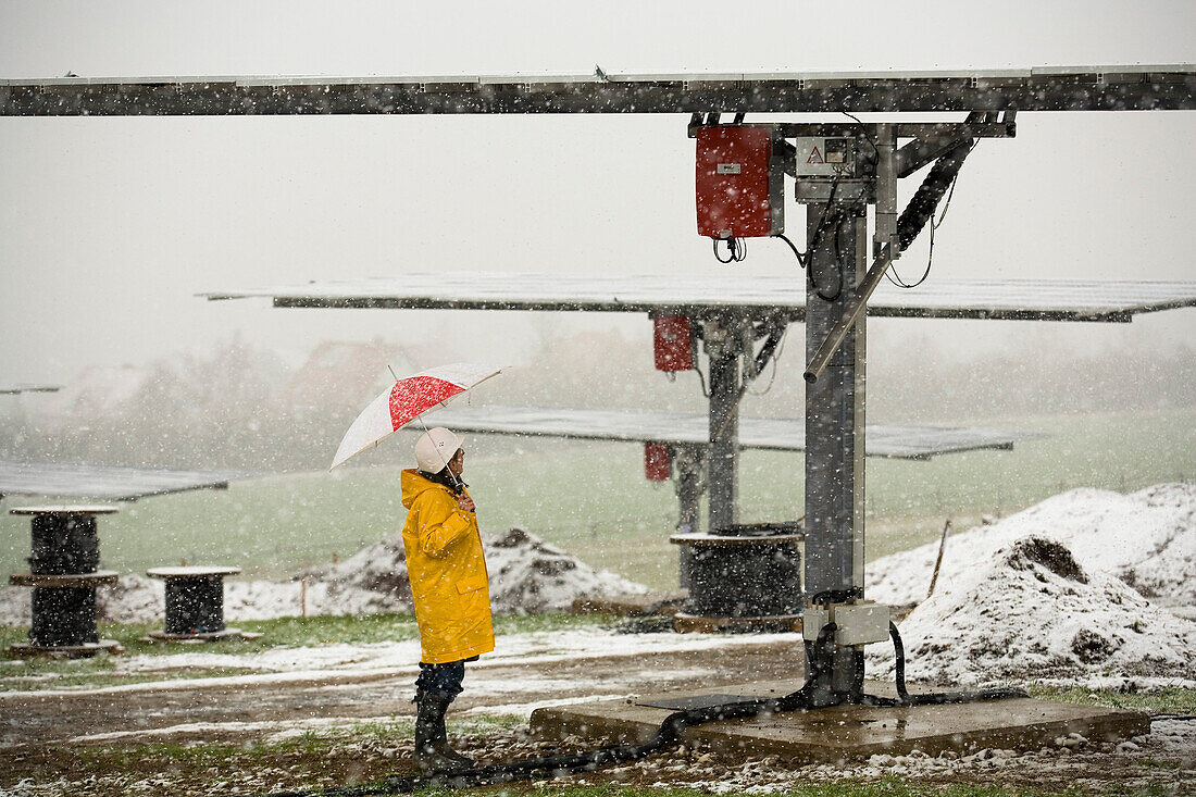 Solarpark im Winter, Frau steht im Schneegestöber mit Regenschirm, Edertal, Hessen, Deutschland, Europa