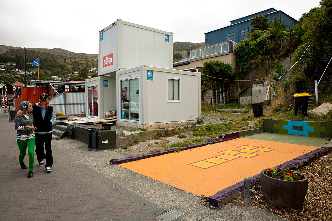 Young couple walking near the foundation of the former Lyttel Arthouse destroyed during the 2011 earthquake, Lyttelton, near Christchurch, Canterbury, South Island, New Zealand