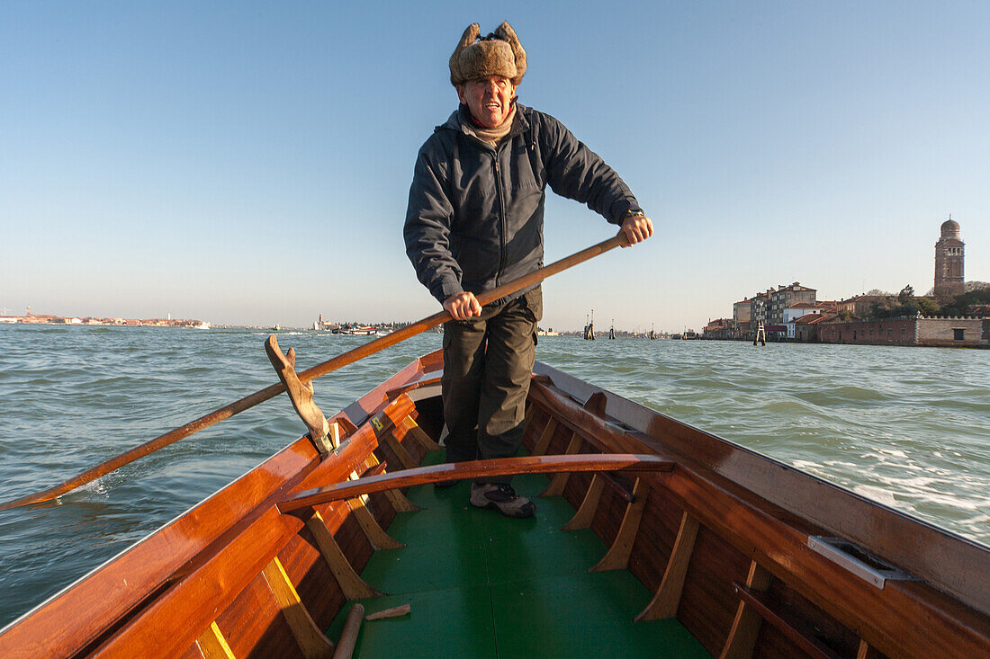 Ruderlehrer rudert ein traditionelles Holzboot Sandolo, Lagune von Venedig, Italien