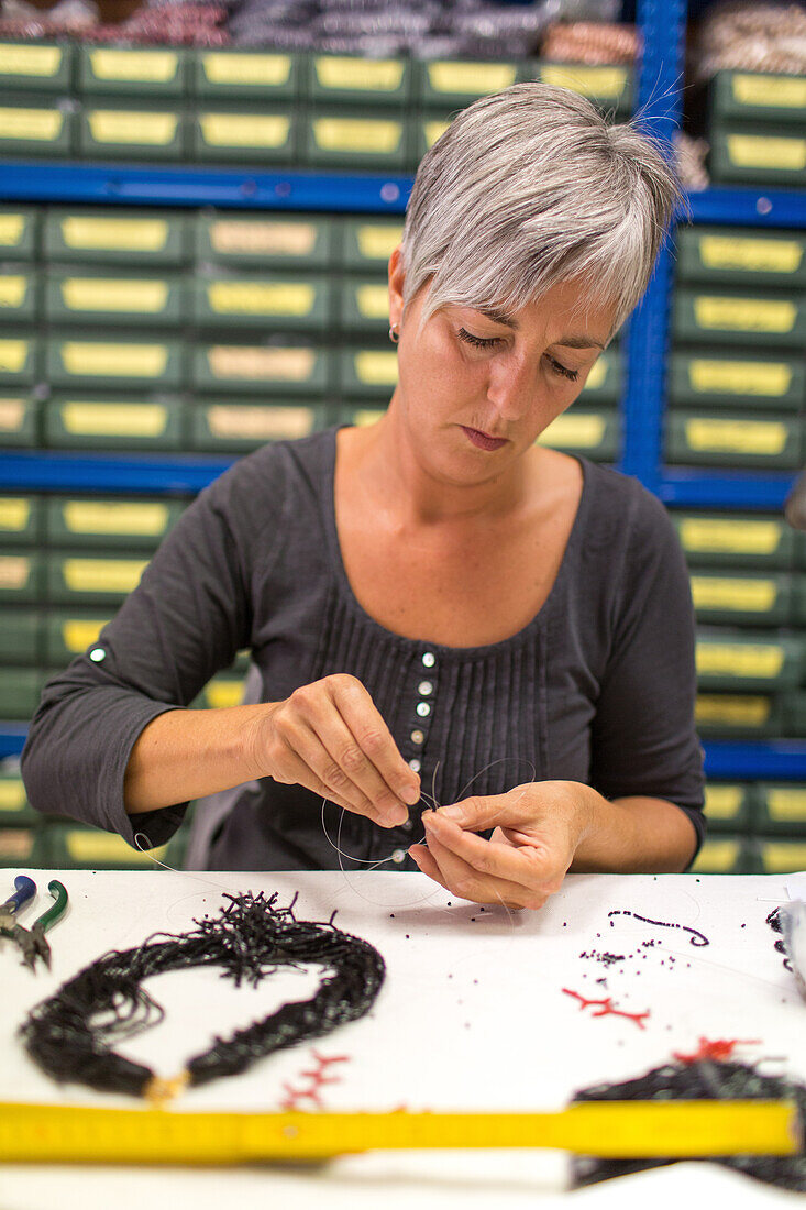 glass bead artist in studio of Luisa Conventi, Atelier Gioia, threading beads, jewellery, Venice, Italy