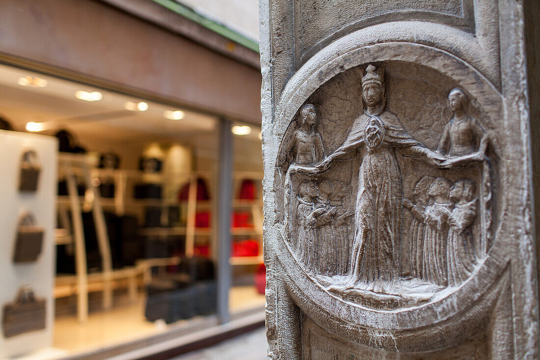 Steintafel, Relief aus dem frühen Mittelalter, Gasse mit modernem Schaufenster im Hintergrund, Venedig, Italien