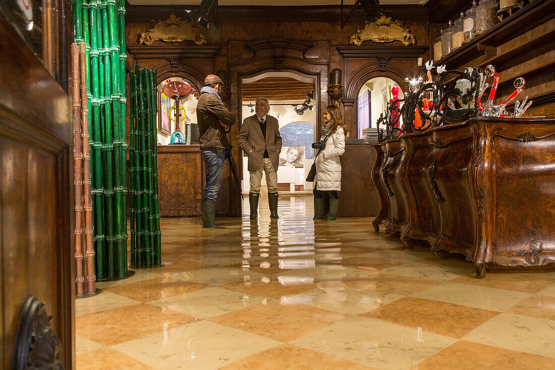 Acqua Alta, high water, Paolo Juris in rubber boots, in the Berengo Gallery, San Marco, famous contemporary glass objects made in Murano by international artists, Venice, Italy