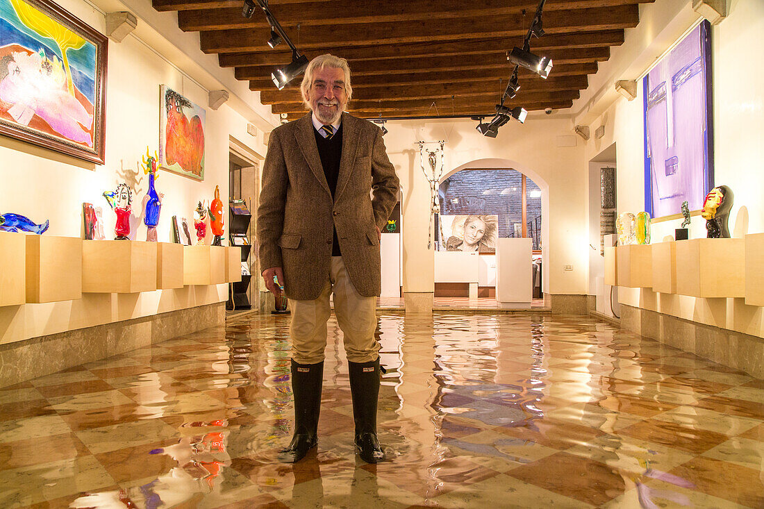 Acqua Alta, high water, Paolo Juris in rubber boots, in the Berengo Gallery, San Marco, famous contemporary glass objects made in Murano by international artists, Venice, Italy
