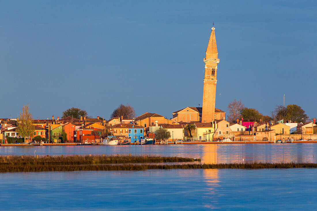 Burano Island, colourful houses, leaning campanile, tower, view from lagoon, evening sun, Venice, Italy