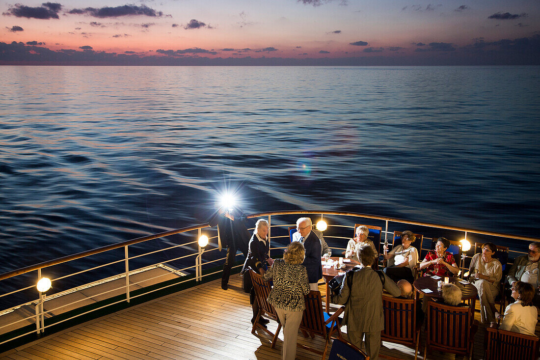 Blitzlicht von Fotograf bei Geburtstagsfeier an Deck von Kreuzfahrtschiff MS Deutschland (Reederei Peter Deilmann) in der Abenddämmerung, Mittelmeer, nahe Italien, Europa